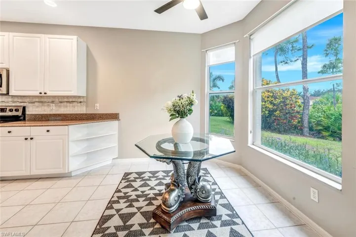 Kitchen with ceiling fan, decorative backsplash, range, and white cabinetry