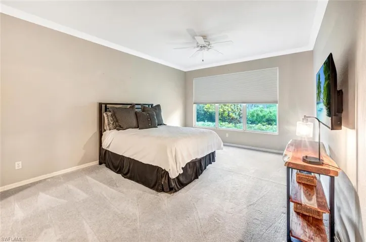 Bedroom featuring ceiling fan, light colored carpet, and ornamental molding