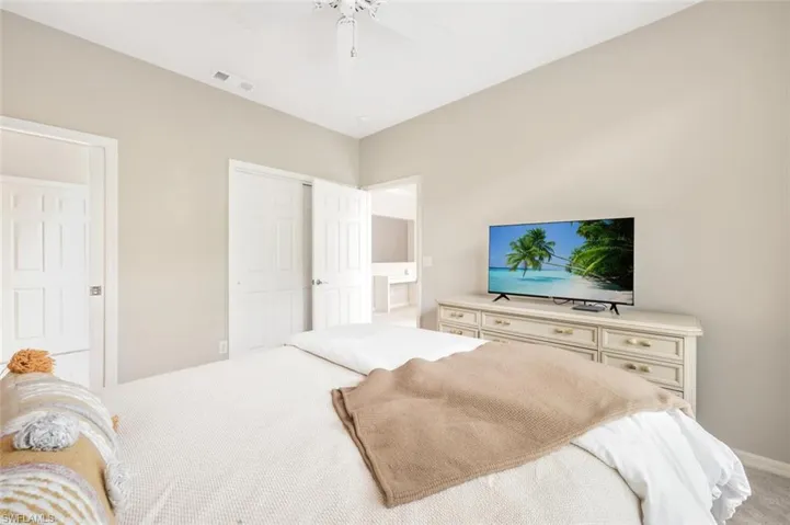 Carpeted bedroom featuring connected bathroom and ceiling fan