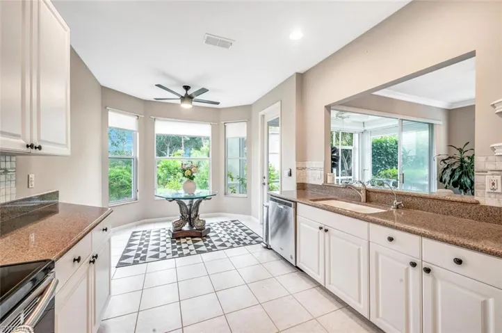 Kitchen with plenty of natural light, sink, white cabinets, stainless steel appliances, and ceiling fan