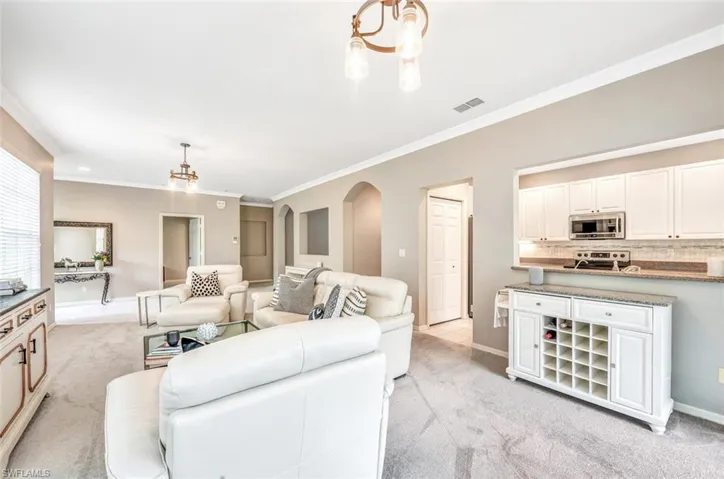 Carpeted living room with ornamental molding and an inviting chandelier