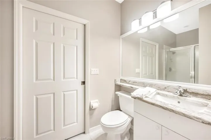 Bathroom featuring tile patterned flooring, vanity, toilet, and an enclosed shower