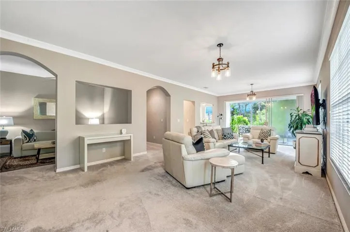 Carpeted living room featuring a notable chandelier and crown molding