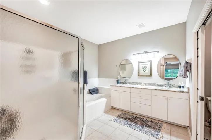 Bathroom featuring vanity, tile patterned flooring, and separate shower and tub