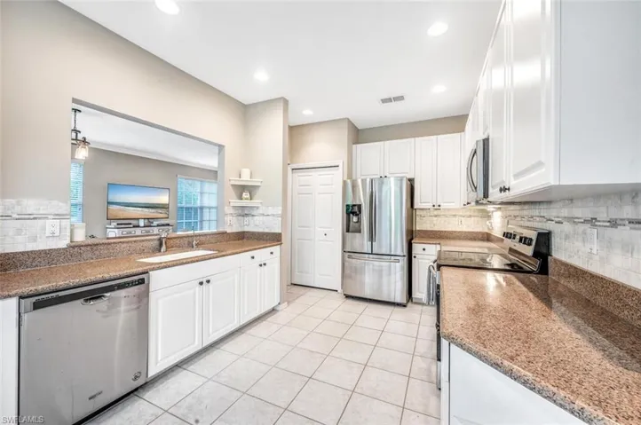 Kitchen with light tile flooring, sink, white cabinetry, and stainless steel appliances