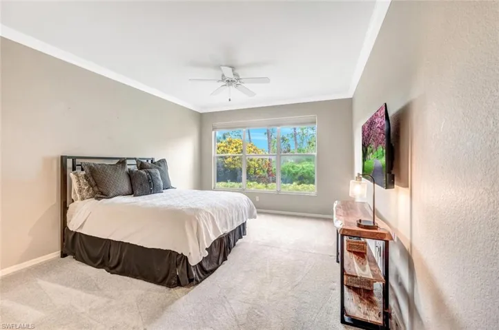 Carpeted bedroom with ornamental molding and ceiling fan