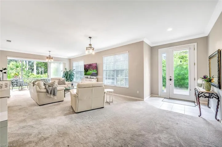 Living room featuring ornamental molding, light carpet, and a notable chandelier