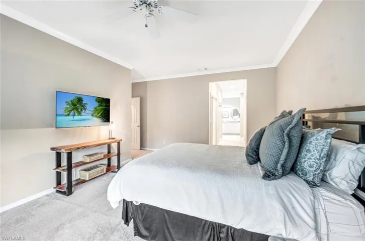 Carpeted bedroom with ornamental molding, connected bathroom, and ceiling fan