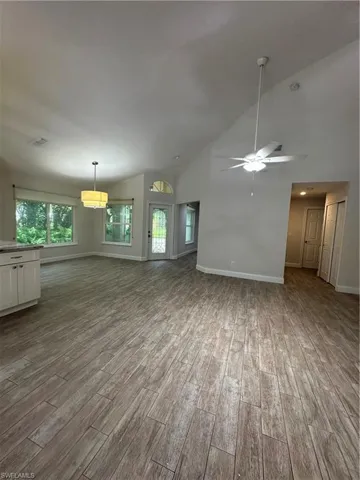 Vaulted ceilings, wood-finish flooring, white cabinetry, ceiling fan, and recessed lighting