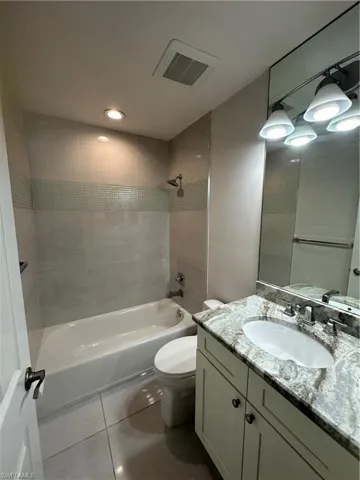 Bathroom featuring a single vanity with stone countertop, integrated sink, and white cabinetry
