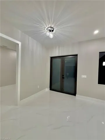 Empty room with light marble finish floors, recessed lighting, and a chandelier