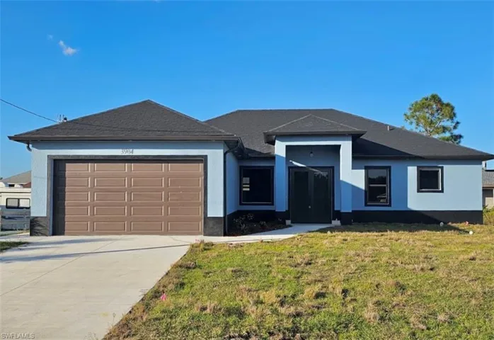 View of front facade with a garage, a front lawn, driveway, and stucco siding