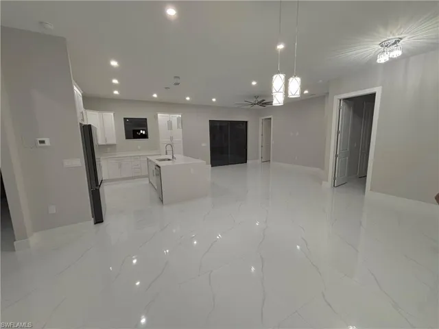 Kitchen with open floor plan, white cabinets, ceiling fan, decorative light fixtures, and recessed lighting