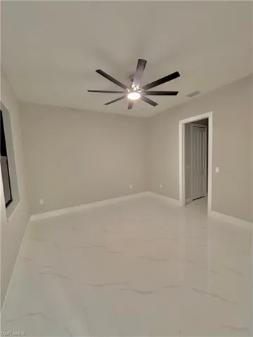 Empty room featuring light marble finish floors and a ceiling fan