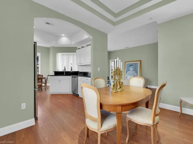 Dining space featuring a raised ceiling, sink, and light hardwood / wood-style flooring