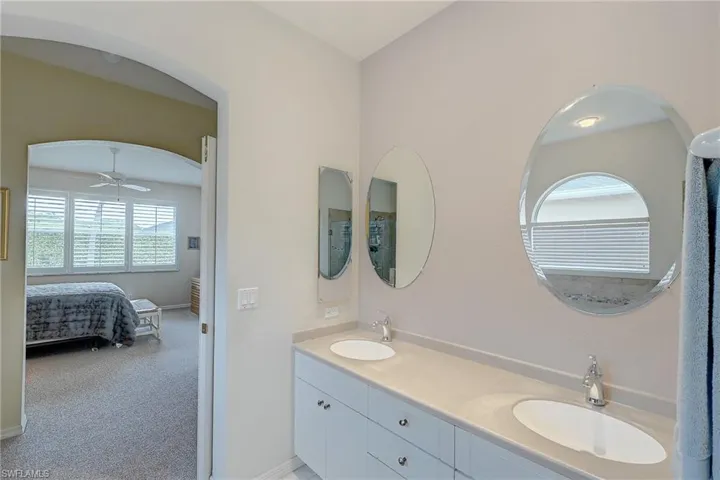 Full bath featuring double vanity, ensuite bathroom, light carpet, and ceiling fan