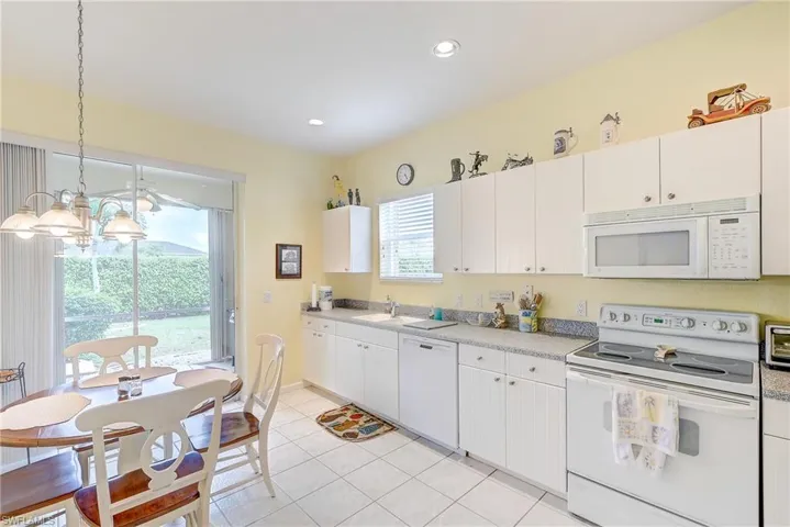 Kitchen featuring white appliances, a chandelier, light countertops, white cabinets, and light tile patterned flooring