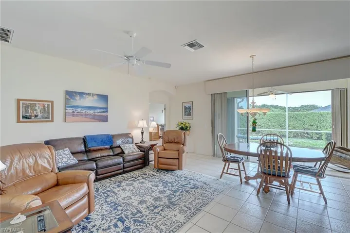 Living area featuring a ceiling fan, light tile patterned floors, and arched walkways