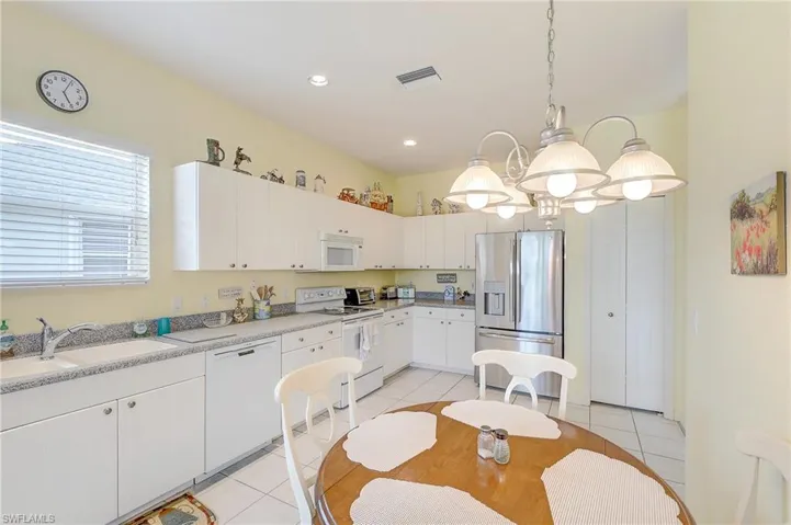 Kitchen featuring white appliances, white cabinets, light tile patterned floors, and light countertops