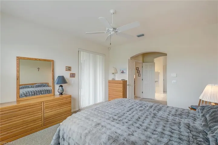 Bedroom with arched walkways, ceiling fan, and light carpet