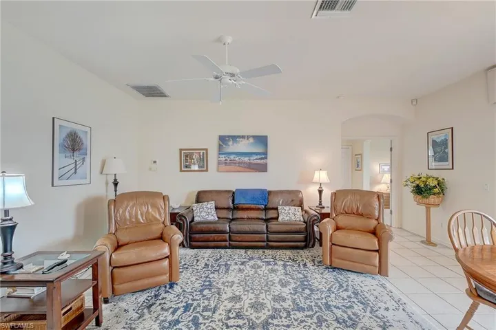 Living area with ceiling fan, arched walkways, and light tile patterned flooring