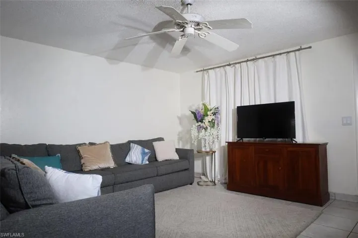 Tiled living room featuring ceiling fan and a textured ceiling