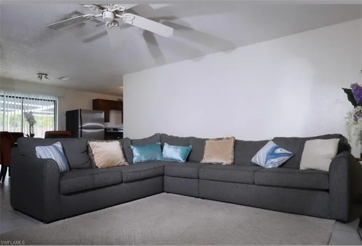 Living room featuring light tile patterned floors, a ceiling fan, and a textured ceiling