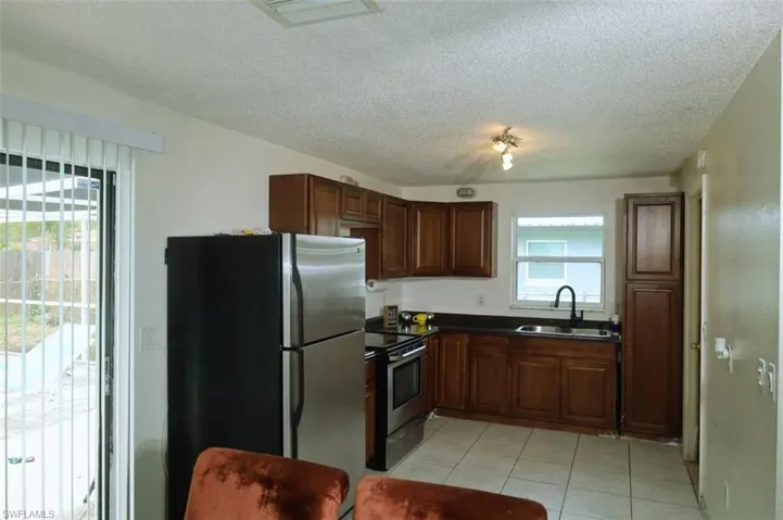 Kitchen with appliances with stainless steel finishes, dark countertops, plenty of natural light, light tile patterned floors, and a textured ceiling