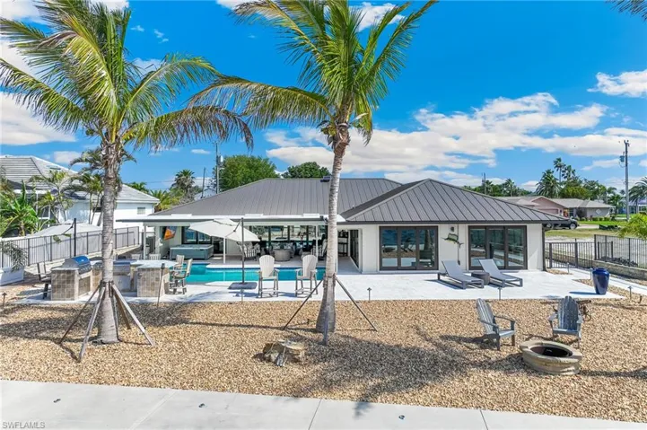 Back of house featuring a fenced backyard, a fire pit, metal roof, and a patio