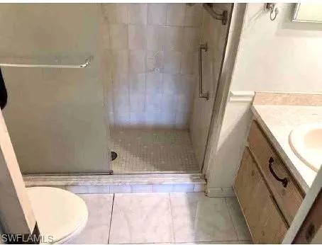 Bathroom with an enclosed shower, vanity, toilet, and tile floors