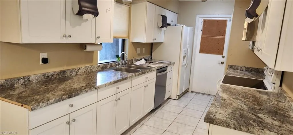 Kitchen featuring white cabinetry, sink, stainless steel dishwasher, and microwave