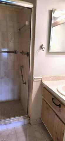 Bathroom with a shower with door, vanity, and tile patterned floors