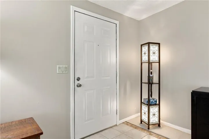 White paneled entry door with polished chrome hardware and ceramic tile flooring