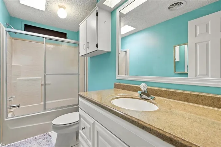 Single vanity with a light-toned countertop, white cabinetry, and an integrated sink