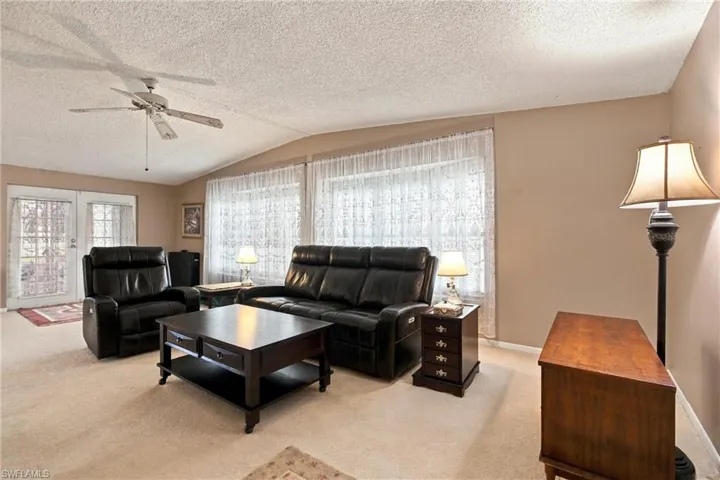 Vaulted ceilings with a ceiling fan, wall-to-wall carpeting, and French doors