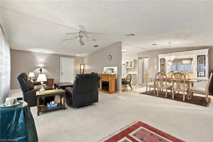 Dining area with a decorative chandelier, built-in display cabinetry, and a pass-through window to the kitchen