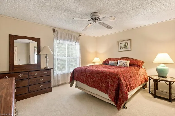 Soft neutral wall paint, textured ceiling, ceiling fan, and carpeted flooring