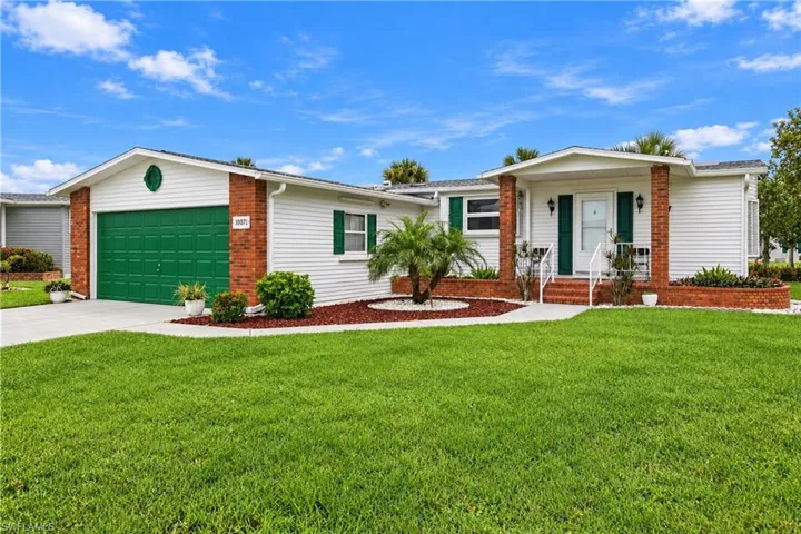 White exterior siding with brick accents, green garage door, green window shutters, concrete driveway, and front entry with white columns