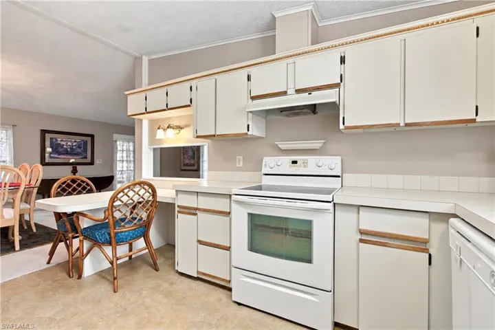 Kitchen featuring white cabinetry, white electric range, white dishwasher, tile countertops, and a pass-through window