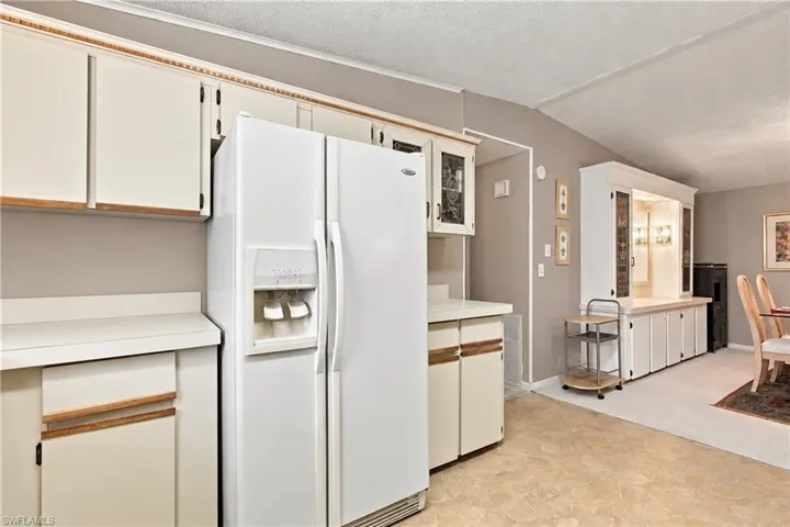 Kitchen featuring white cabinetry, solid surface countertops, white side-by-side refrigerator, and built-in display cabinetry