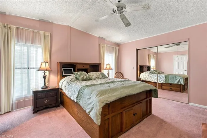 Recessed window with blinds, ceiling fan, mirrored closet doors, and textured ceiling