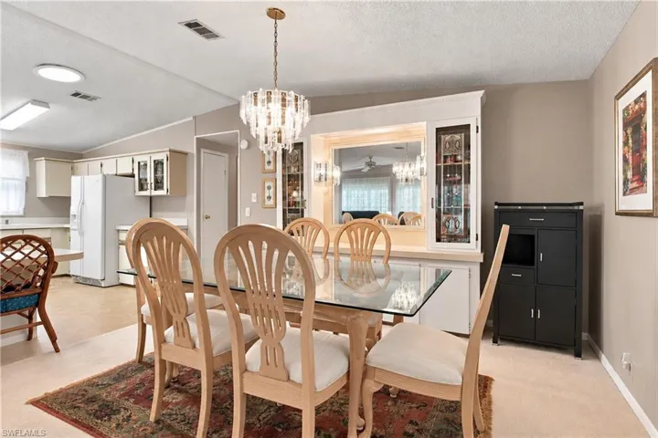 Open-concept dining area featuring a crystal chandelier and a built-in display cabinet with mirror