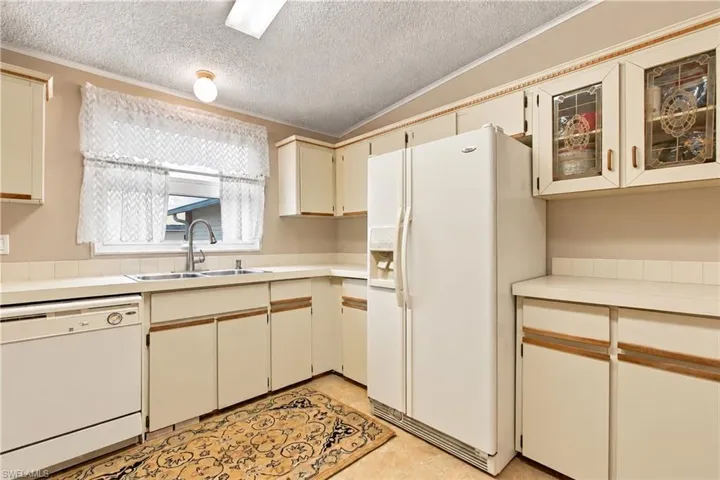 Kitchen with neutral-toned cabinetry, a stainless steel double-basin sink, and a built-in dishwasher