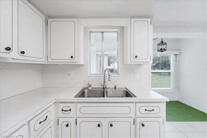 Kitchen with light countertops, white cabinetry, and backsplash