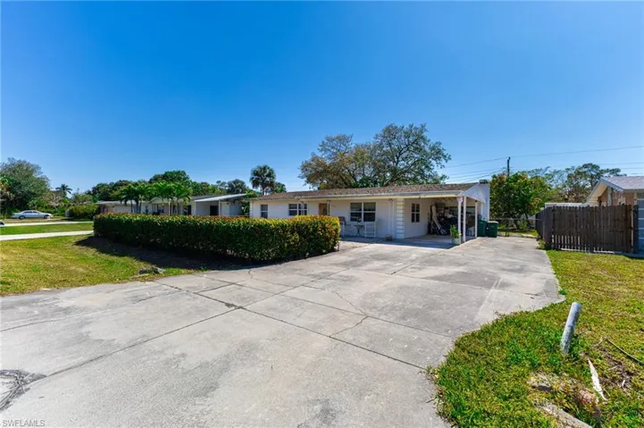Ranch-style house featuring a carport, a front yard, fence, and driveway
