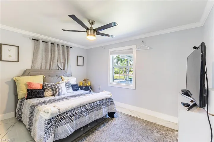 Bedroom featuring marble finish floor, crown molding, baseboards, and ceiling fan
