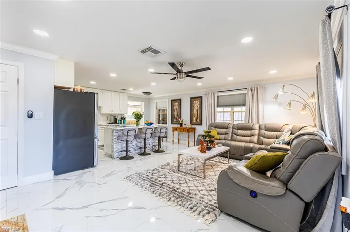 Living room with marble finish floor, ornamental molding, and visible vents