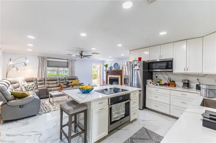 Kitchen featuring white cabinets, open floor plan, appliances with stainless steel finishes, tasteful backsplash, and crown molding