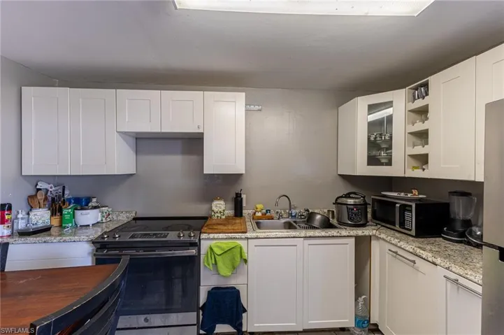 Kitchen featuring appliances with stainless steel finishes, glass insert cabinets, and white cabinets