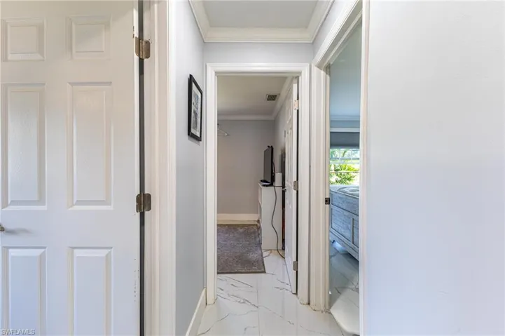 Hallway featuring marble finish floor, baseboards, and crown molding